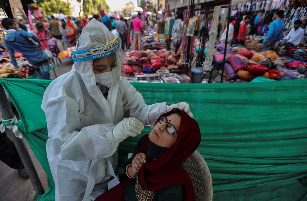 Un trabajador de la salud toma una muestra de hisopado nasal de una mujer para realizar la prueba de COVID-19 en una instalación construida en un mercado en Ahmedabad, India. Foto: AP