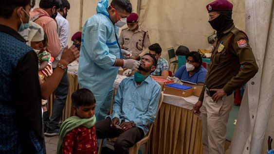 Un trabajador de la salud toma una muestra de hisopado nasal de un pasajero para realizar la prueba de coronavirus en una terminal de autobuses en Nueva Delhi, India. Foto: AP