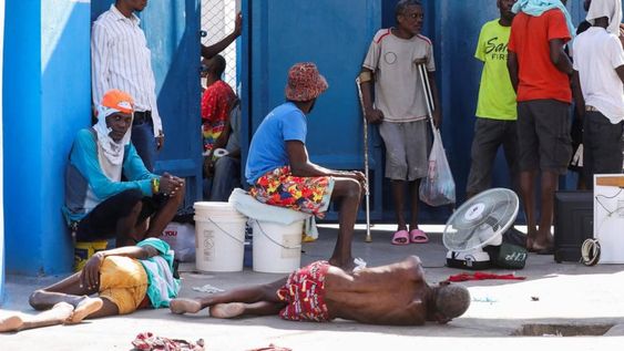 Los reclusos descansan en el suelo de la Penitenciaría Nacional tras violentos enfrentamientos en la capital que dañaron las comunicaciones y provocaron una fuga de esta prisión en Puerto Príncipe.
