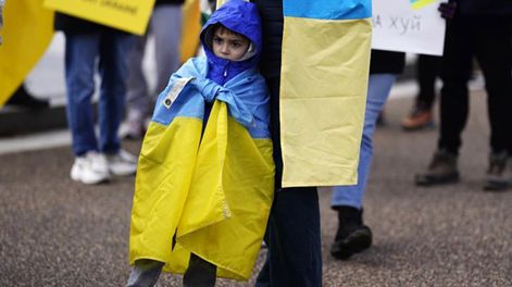 Un niño ucraniano refugiado junto a su padre en una manifestación. Foto: EFE
