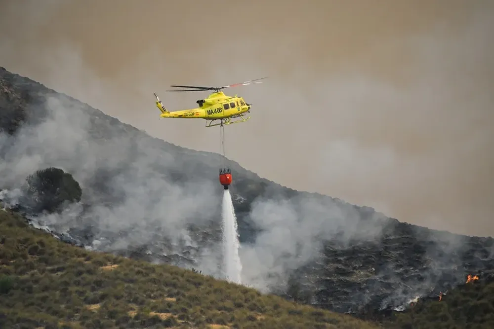 Un helicóptero del servicio de extinción de incendios arrojaba este viernes agua sobre uno de los focos del incendio de Los Gallardos.