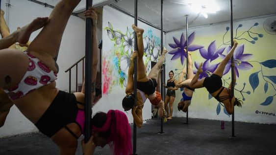 Mujeres y hombres practican Pole Dance, una disciplina que combina arte y deporte que exige un gran esfuerzo y despliegue físico para lograr las formas estéticas en la barra. / Foto: Claudio Gutierrez