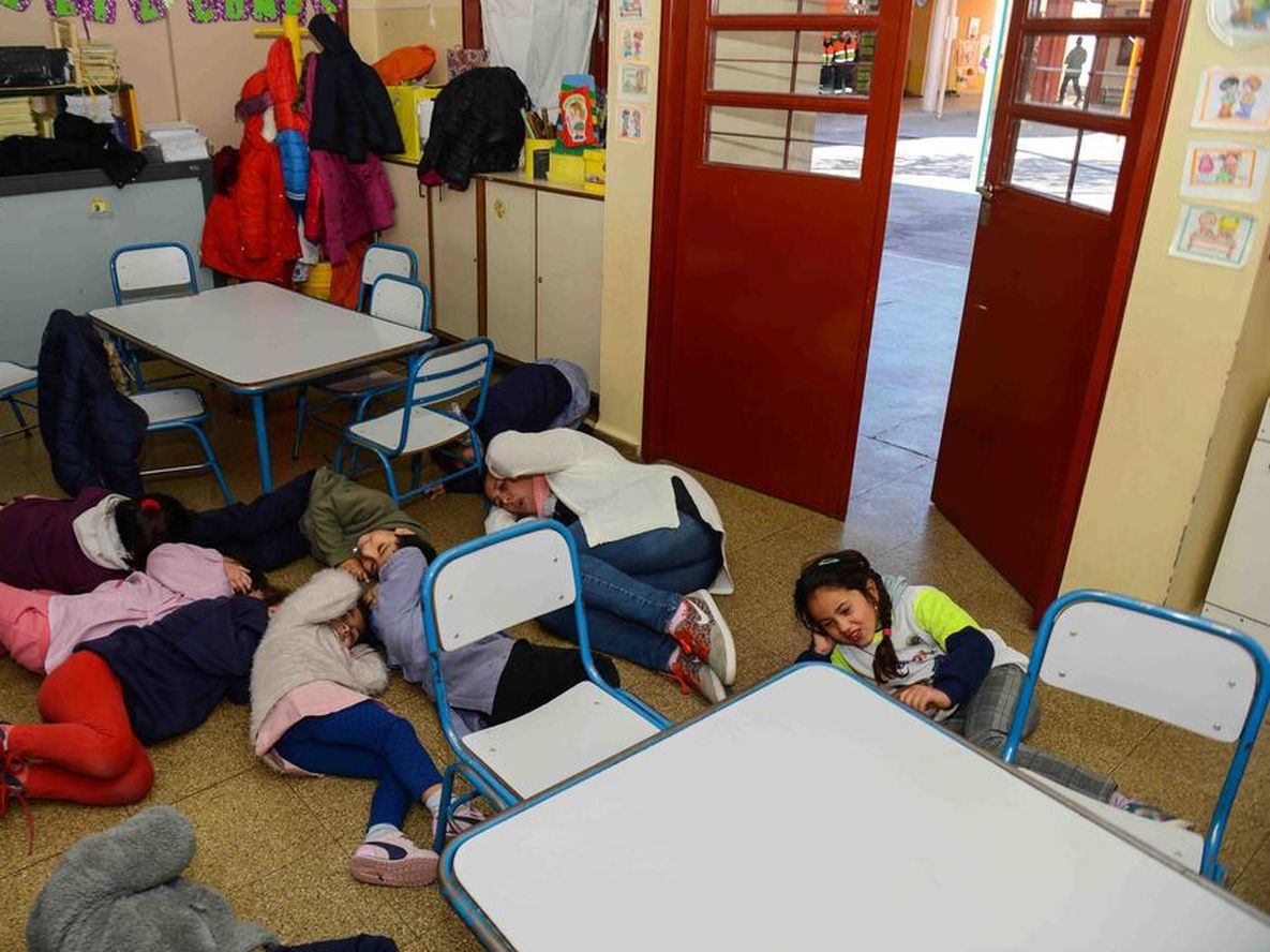 Simulacro. Niños durante un ejercicio sísmico en una escuela. Se cubren la cabeza y permanecen tirados en el suelo.