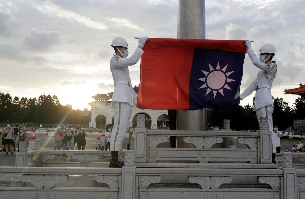 ARCHIVO - Dos soldados doblan la bandera nacional durante la ceremonia diaria de izado de bandera en la plaza Liberty en Taipéi, Taiwán, el 30 de julio de 2022. Taiwán dijo el lunes que seis globos chinos pasaron o bien sobre su isla o por el espacio aéreo justo al norte, y también se detectaron aviones y barcos militares chinos en la zona. (AP Foto/Chiang Ying-ying, Archivo)