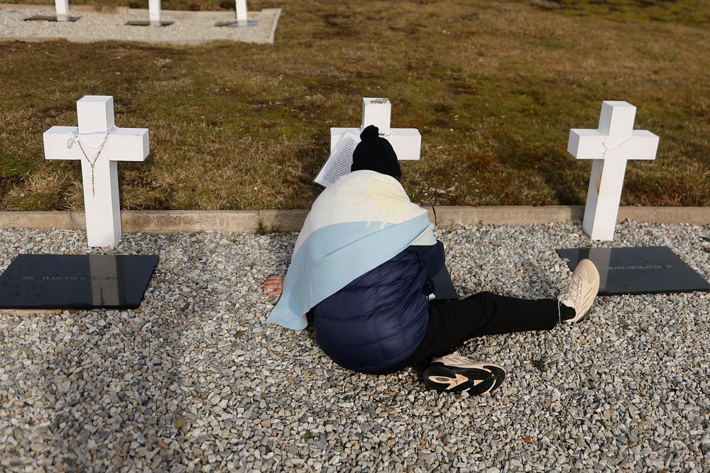 Un familiar de un soldado caído en la guerra de Malvinas reza en el cementerio de Darwin.
