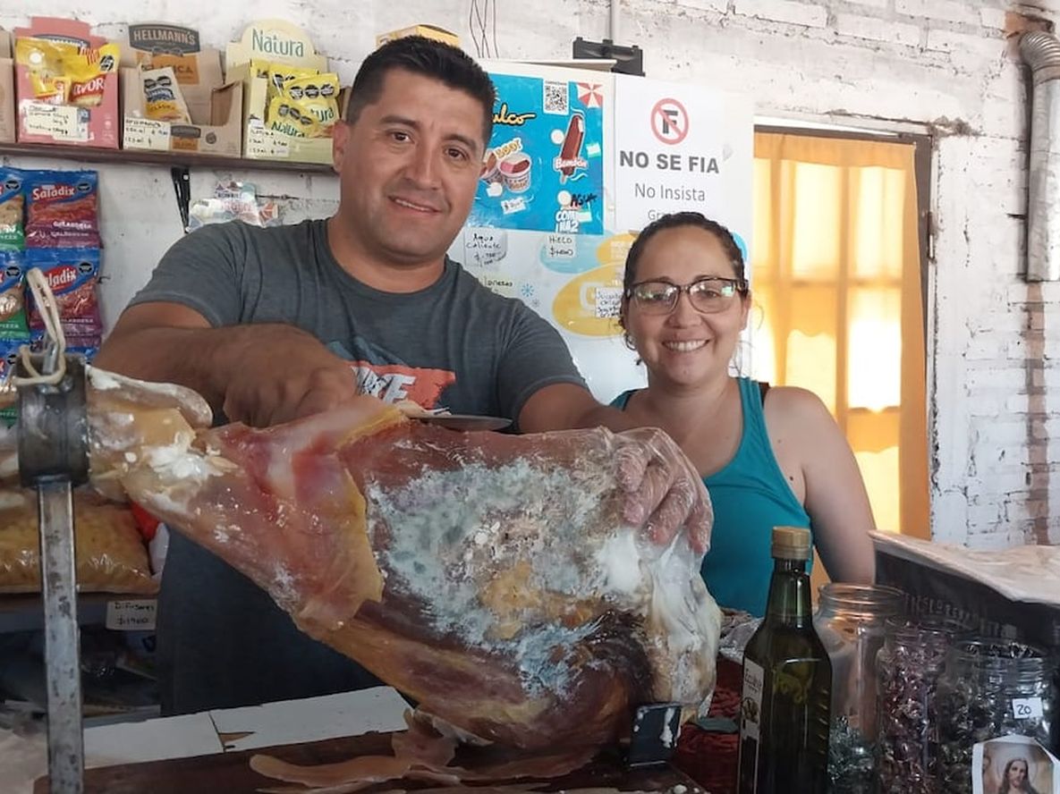 Alejandro y Natalia en su negocio, mostrando los jamones de San Rafael. | Foto: gentileza
