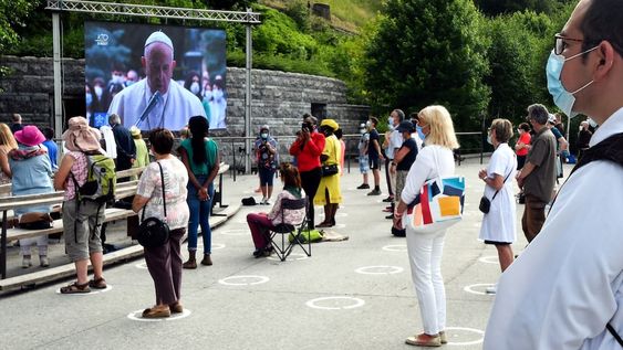 Fieles con máscaras protectoras siguen las medidas de distanciamiento social en la Grotte de Massabielle en el Santuario de Nuestra Señora de Lourdes, en Lourdes. AFP