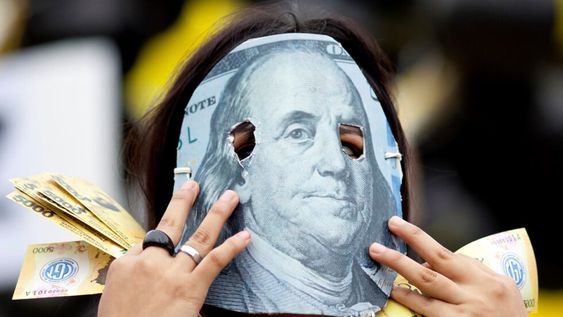 Una persona enmascarada con un detalle de un billete de 100 dólares, en protesta contra el acuerdo que firmó el gobierno de Mauricio Macri con el FMI.