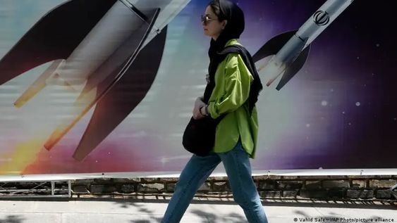 Una mujer camina junto a una pancarta que muestra el lanzamiento de misiles, en el norte de Teherán el viernes 19 de abril de 2024. En los misiles, la palabra con la que son decorados reza: Alá (Dios).
