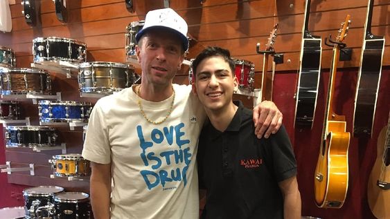 Martin junto a uno de los vendedores que lo recibió. El inglés tocó junto a los trabajadores del local y les regaló entradas. (Twitter).
