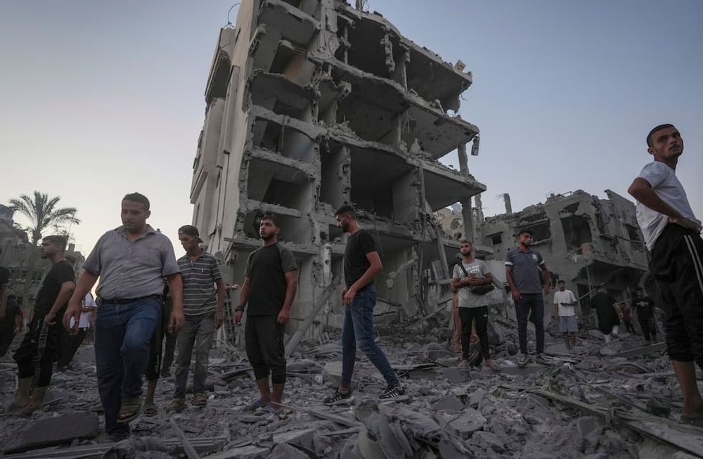 Palestinos caminan sobre los escombros dejados por un bombardeo israelí contra en Deir al Balah, en la Franja de Gaza, el martes 6 de agosto de 2024. (AP Foto/Abdel Kareem Hana)