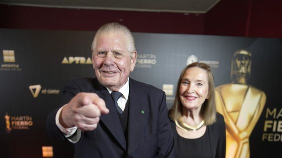 El conductor realiza el clásico gesto que acompaña a su frase Conociendo, en la última gala de los Martín Fierro Federal. Detrás, la infaltable compañía de su esposa, Vidalina Gavlosky.