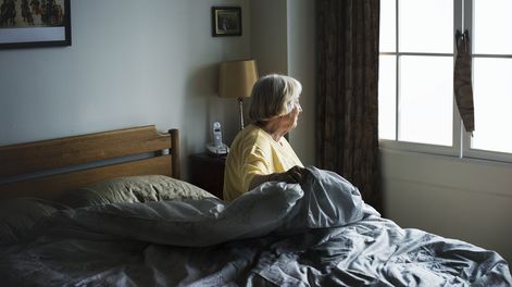 Una mujer enferma mira por la ventana de su habitación. Foto: Freepik.