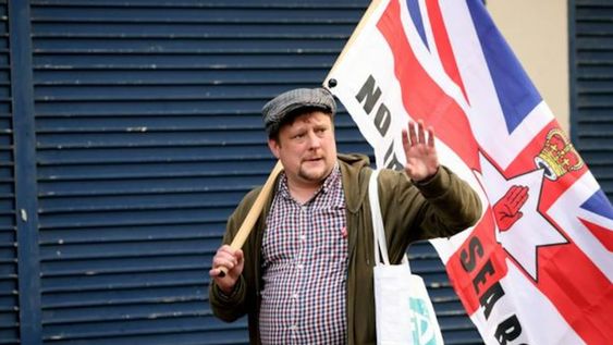 Irlanda del Norte. Un ciudadano protesta con la bandera de Reino Unido y la de Irlanda del Norte por los corredores marítimos comerciales. Imagen de archivo de junio de 2022.