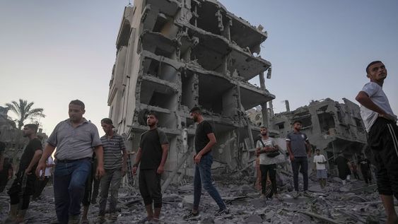 Palestinos caminan sobre los escombros dejados por un bombardeo israelí contra en Deir al Balah, en la Franja de Gaza, el martes 6 de agosto de 2024. (AP Foto/Abdel Kareem Hana)
