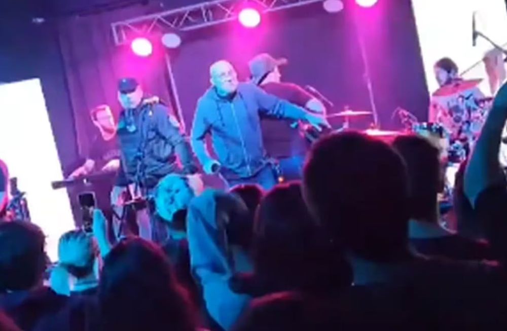 La gente insultó y arrojó bebidas y objetos al policía que se quedó parado al lado de los músicos hasta que terminaron el show - Captura