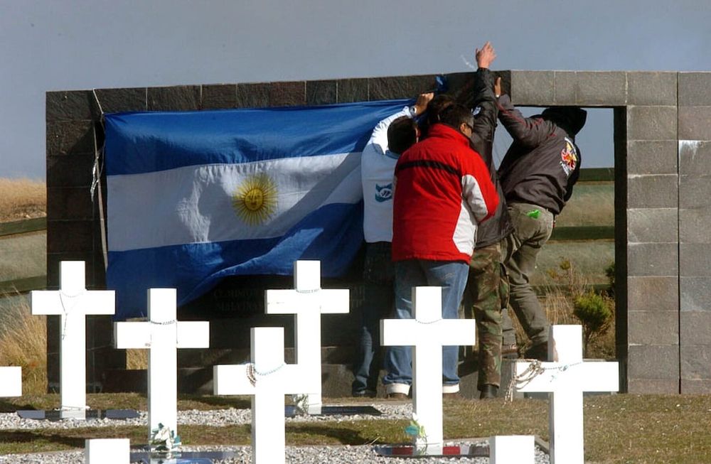 Excombatientes  cuelgan la bandera argentina en el cementerio de Darwin. (Marcela Marbián)