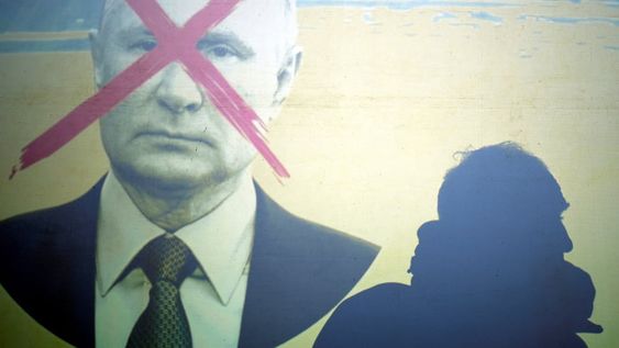 La silueta de un hombre en una pantalla que representa al presidente de Rusia, Vladimir Putin, durante una manifestación contra la invasión rusa de Ucrania. (AP)