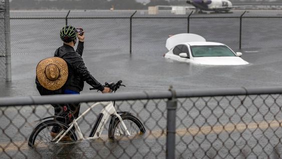 Una persona toma fotografías de un automóvil que está varado en el agua de la inundación en la carretera West Perimeter del Aeropuerto Internacional de Fort Lauderdale en Fort Lauderdale, Florida. Foto: EFE/EPA/CRISTOBAL HERRERA-ULASHKEVICH