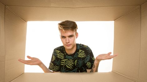 Un joven mira el interior de una caja y descubre que está vacía o que no hay nada. Foto: Freepik.