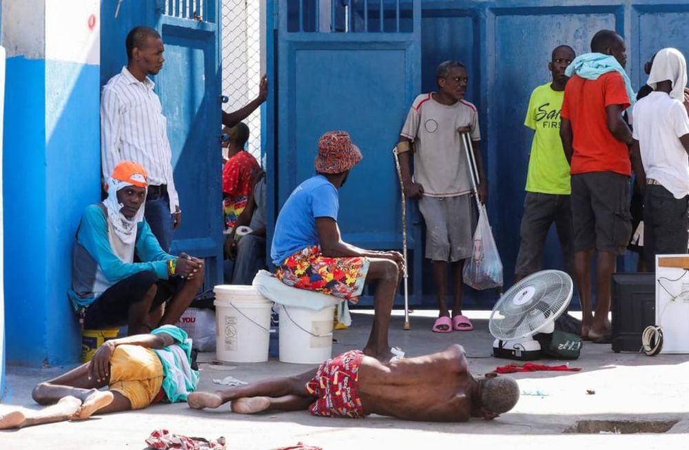 Los reclusos descansan en el suelo de la Penitenciaría Nacional tras violentos enfrentamientos en la capital que dañaron las comunicaciones y provocaron una fuga de esta prisión en Puerto Príncipe.