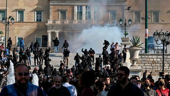 La gente huye de los gases lacrimógenos en el centro de Atenas el 9 de noviembre de 2022 después de que un grupo de jóvenes arrojara cócteles molotov durante las protestas.