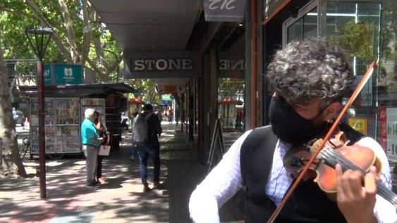 Vestido de manera muy elegante, Miguel Lucena toca su violín en la avenida San Martín.