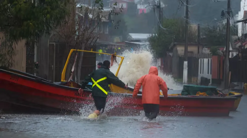 Pescadores del sector Cerro Verde Bajo, en Penco (Chile), intentan rescatar sus botes que son arrastrados por el agua que ingresó por las marejadas