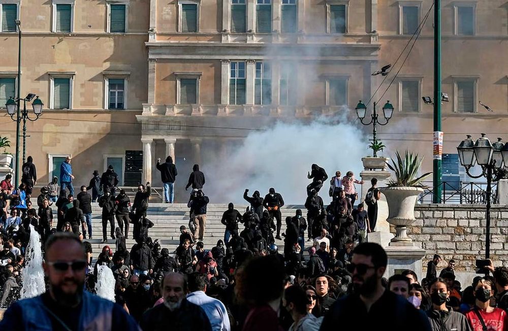 La gente huye de los gases lacrimógenos en el centro de Atenas el 9 de noviembre de 2022 después de que un grupo de jóvenes arrojara cócteles molotov durante las protestas.