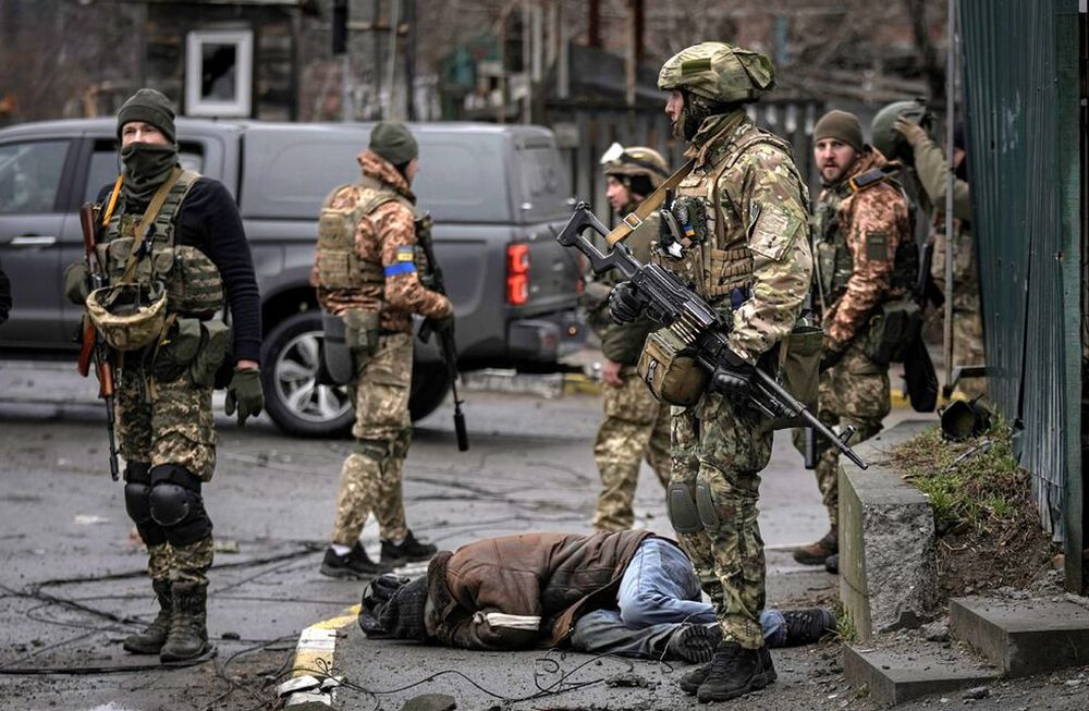 Soldados ucranianos revisan cuerpos de civiles en busca de trampas explosivas en el suburbio de Bucha, Ucrania, anteriormente ocupado por Rusia. (AP)